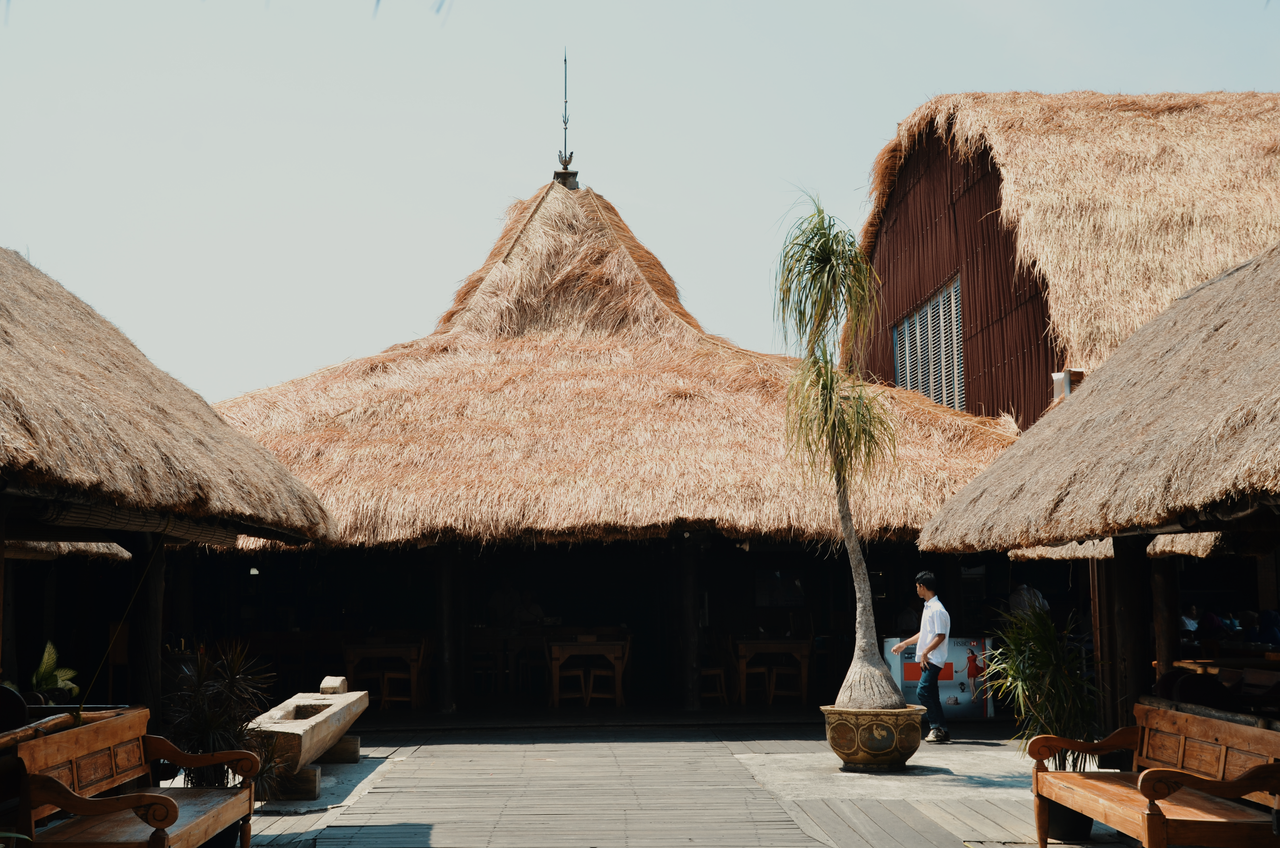 Charming tropical resort-style bungalows with thatched roofs, perfect for a summer getaway.