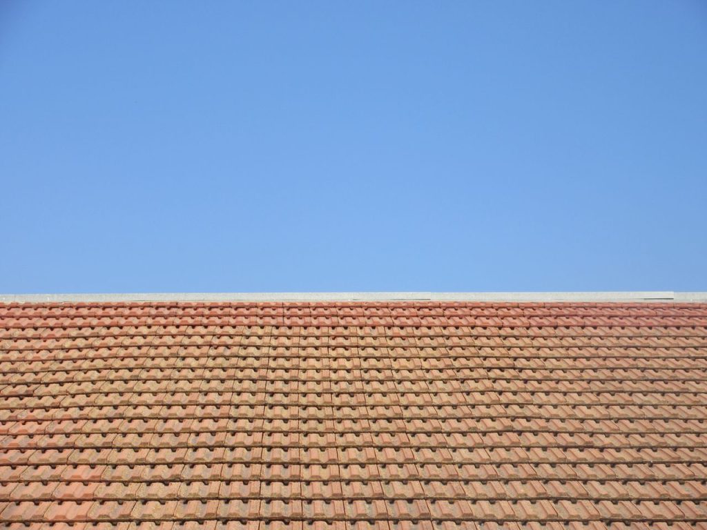Terracotta roof tiles under a clear blue sky, capturing architectural simplicity and outdoor tranquility.
